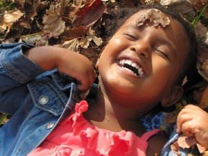 Yemi (4) laughing in leaves